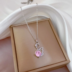 Silver titanium steel swan necklace with pink gemstone pendant on a gold jewelry box