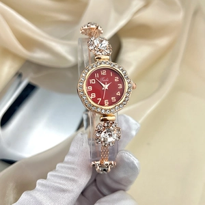 Detail of a ladies' quartz watch with red dial and crystal-encrusted gold band on silk