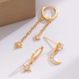 Macro detail of gold celestial earrings set featuring star and moon charms with zircon