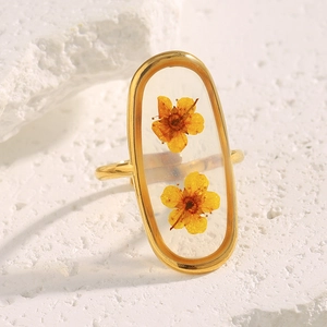 Detailed close-up of 18K gold plated ring with dried yellow flowers in clear resin