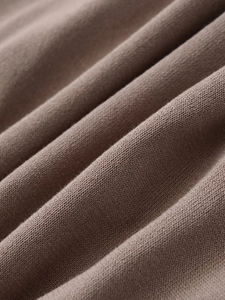 Macro shot of taupe knit fabric texture showing premium soft weave and fiber details