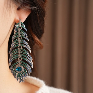 Macro shot of vintage peacock feather earrings with green and blue crystal inlay