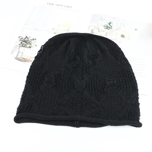 Detailed view of the black crochet knit pattern and scalloped hem of this beanie