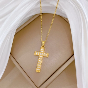 Elegant gold cross necklace with zircon stones on beige velvet and silk fabric display