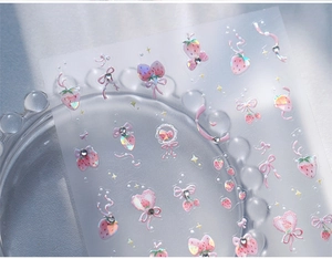 Detail of pink strawberry nail art stickers with laser holographic finish and rhinestones