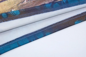 Detailed close-up of fabric texture with intricate print and blue double-stitch seams