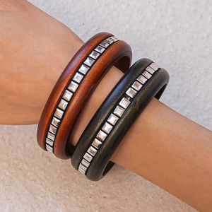 Détail macro de bracelets en bois avec clous carrés argentés et texture rustique vintage