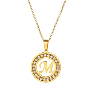 Detailed macro view of a gold-plated necklace with a zircon-encrusted round letter M pendant