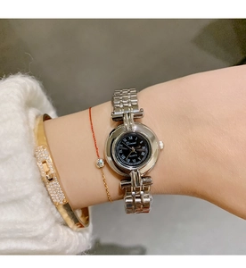 Close-up of elegant silver steel watch featuring a black dial and Roman numerals on wrist