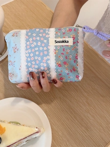 Floral cotton pouch with lace details and purple wrist strap in a lifestyle setting