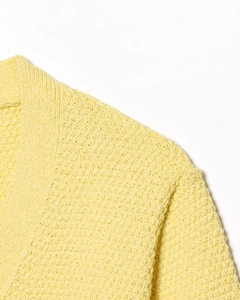 Détail du pull en maille jaune citron montrant le motif gaufré et la couture d'épaule