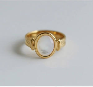 Detailed view of a gold oval ring with polished white mother of pearl inlay and fluted band