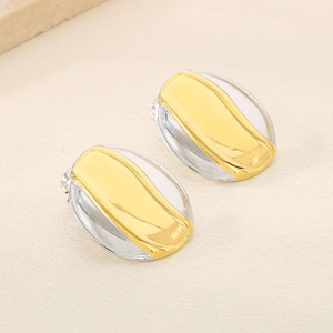 Détail de boucles d'oreilles ovales bicolores avec finitions en métal poli or et argent