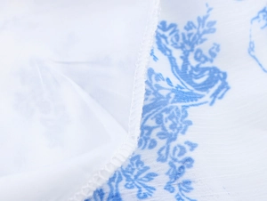 Makroaufnahme des weißen Blumenstoffs mit blauen Drucken und hochwertiger Kantennaht