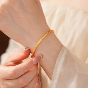 Detailed close-up of a vintage brushed gold bangle set with small sparkling diamonds