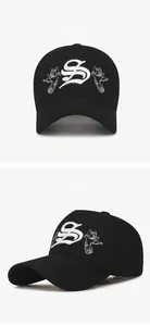 Detail of white dove and letter S embroidery on a black 5-panel adjustable sports cap