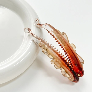 Elegant amber gradient banana hair clip with bow design on a white ceramic plate