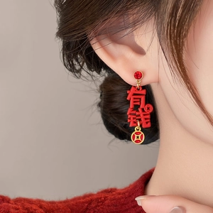 Close-up of asymmetrical horse pendant earring with red stone and lucky coin detail