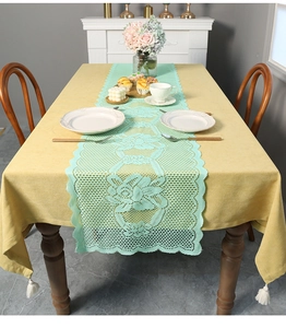 Detailed close-up of mint green floral lace table runner with elegant white tassels