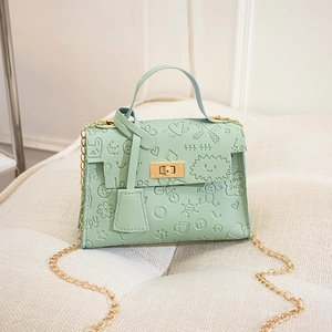 Detail of mint green Kelly handbag featuring embossed cartoon patterns and gold chain strap