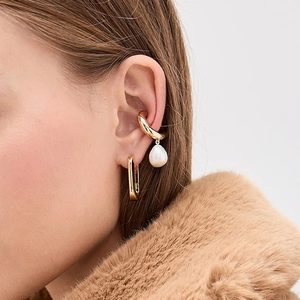 Élégantes boucles d'oreilles en acier titane doré avec perles sur un mannequin