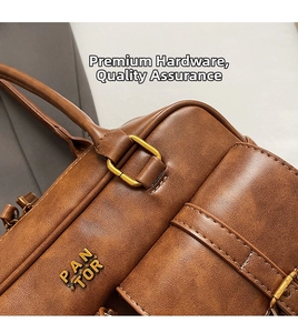Close-up of golden PAN TOR logo and premium hardware on brown vintage leather bag
