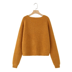 Close-up of ginger yellow crewneck knit sweater showing ribbed cuffs and hem texture