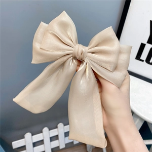 Detail of a oversized champagne organza bow hairclip showing its multi-layered texture