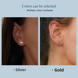 Minimalist heart stud earrings in polished gold and silver finishes shown on ears
