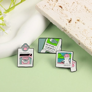 Set of 3 cute cartoon cat enamel pins featuring fishing and reading themes on stones