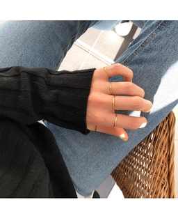 Minimalist stackable gold skinny rings shown on fingers with a cozy lifestyle background