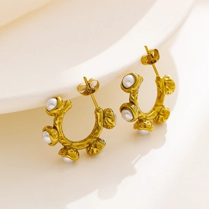Macro shot of French vintage gold textured earrings with elegant white baroque pearls
