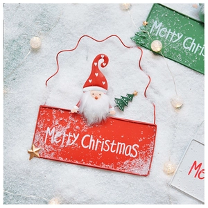 Macro view of metal Merry Christmas signs with Santa figurines on faux snow background