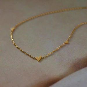 Macro shot of delicate gold heart charms on a fine titanium steel necklace chain