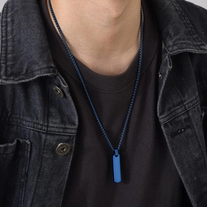 Close-up of a blue stainless steel rectangular pendant necklace worn by a male model