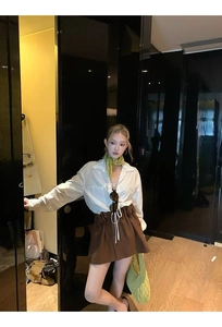 Close-up of women's white blouse and dark brown wool blend high-waisted mini skirt set