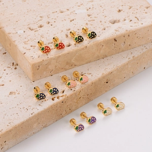 Cute strawberry stud earrings in vibrant enamel colors on a textured stone base