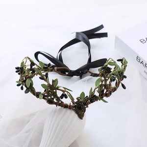 Detail of forest style vine crown with green leaves, black berries and bronze animal motif