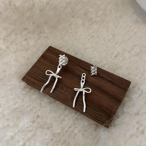 Macro shot of 925 silver bowknot fringe earrings set on a warm textured background