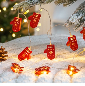 Close-up of red hollowed metal glove LED string lights on snowy Christmas tree