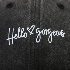 Detail of Hello Gorgeous embroidery and heart icon on washed black cotton baseball cap
