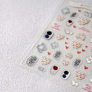 3D silver foil nail art stickers with embossed heart and geometric designs on white texture