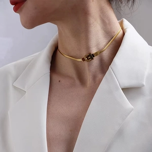 Elegant gold belt buckle necklace with smooth snake chain on white blazer background