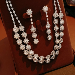 Detail of silver floral tassel necklace and earring set on dark red velvet display