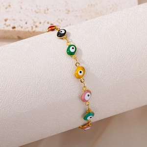 Close-up of colorful evil eye enamel charms on a gold chain bracelet display