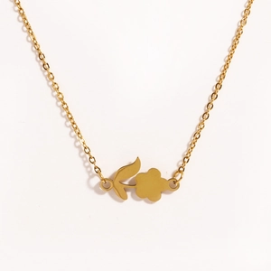 Close-up of golden rose flower and leaf pendant necklace in polished titanium steel