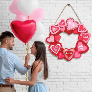 Hanging Valentine heart wreath with red and pink plaid patterns on white brick wall
