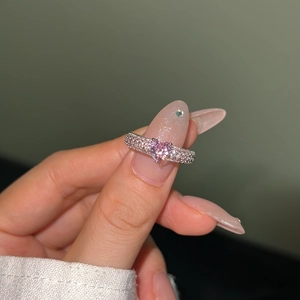 Close-up of heart-shaped pink zircon ring with diamond-encrusted silver band