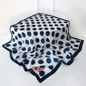 Detailed view of a white polka dot silk scarf featuring a red butterfly accent