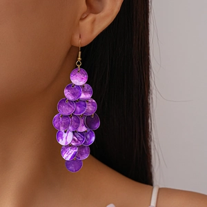 Close-up of long purple sequin shell fringe earrings on model for beach style